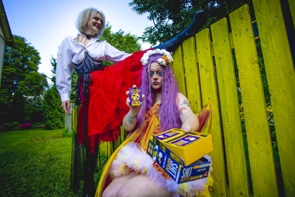 Drag princess CumUnity Cervix offers a reading from an unexpected deck with a piratical friend posing in the background.